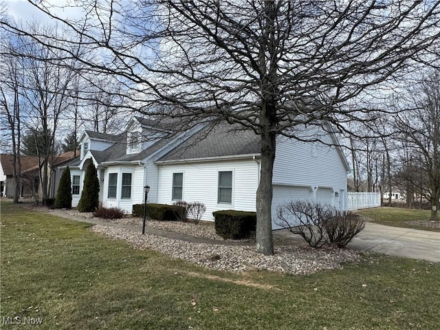 view of home's exterior featuring a garage, a yard, roof with shingles, and driveway