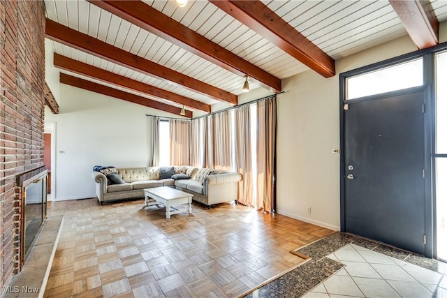 unfurnished living room with a brick fireplace, vaulted ceiling with beams, and baseboards