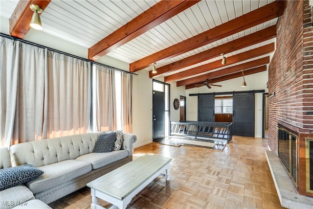 living room with a barn door, a brick fireplace, baseboards, and beam ceiling