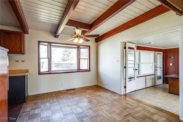 unfurnished dining area featuring a ceiling fan, beam ceiling, baseboards, and visible vents