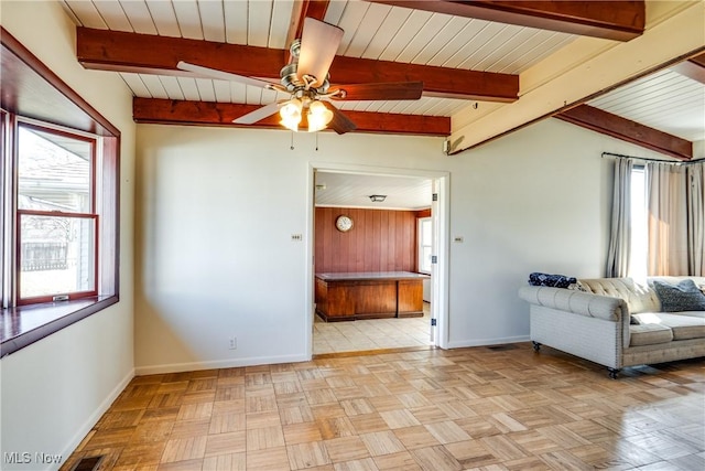 unfurnished living room featuring a ceiling fan, beamed ceiling, visible vents, and baseboards