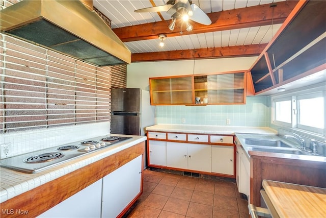 kitchen with dark tile patterned flooring, a sink, backsplash, stainless steel appliances, and exhaust hood