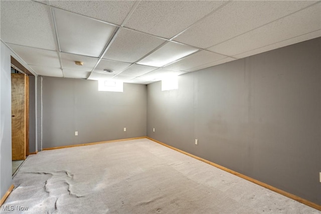 basement with carpet flooring, baseboards, and a drop ceiling