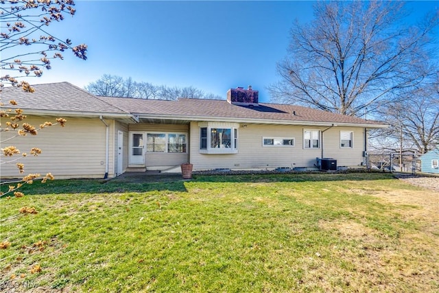 rear view of property with a shingled roof, cooling unit, a lawn, and a chimney