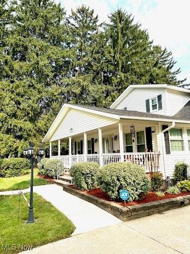 farmhouse-style home featuring covered porch and a front yard