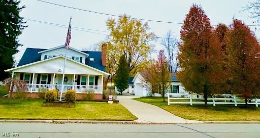 view of front of property featuring a front lawn, concrete driveway, and covered porch