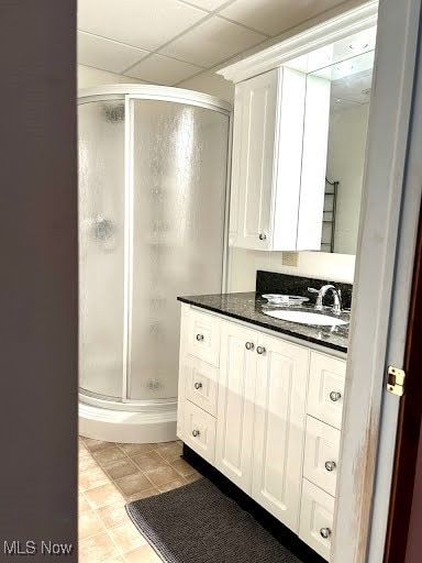 bathroom featuring tile patterned flooring, a shower stall, vanity, and a paneled ceiling