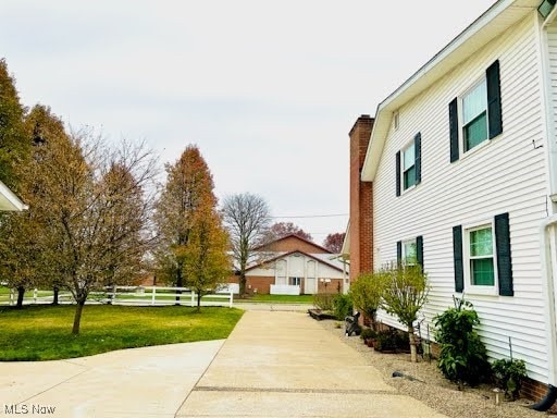 view of home's exterior featuring a chimney, a yard, and fence