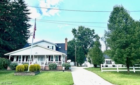 view of front facade with a porch, a chimney, and a front yard