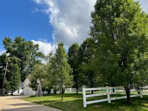 view of property's community featuring a yard, fence, a garage, and driveway