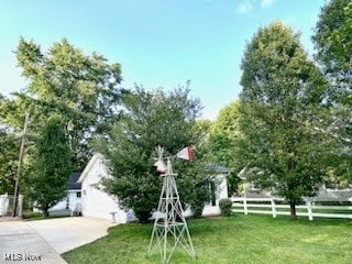 view of yard featuring concrete driveway and fence