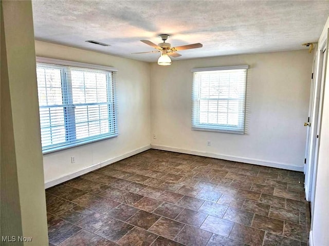 spare room featuring plenty of natural light, baseboards, and visible vents