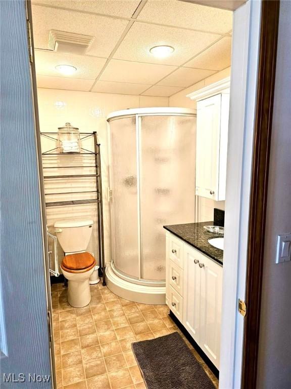 full bath featuring a paneled ceiling, vanity, a shower stall, and toilet