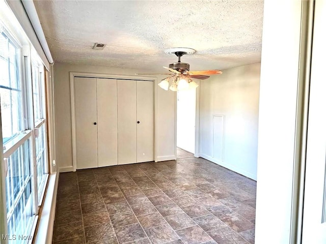 unfurnished bedroom with visible vents, baseboards, a textured ceiling, and a closet