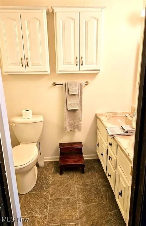 bathroom featuring toilet, vanity, and baseboards