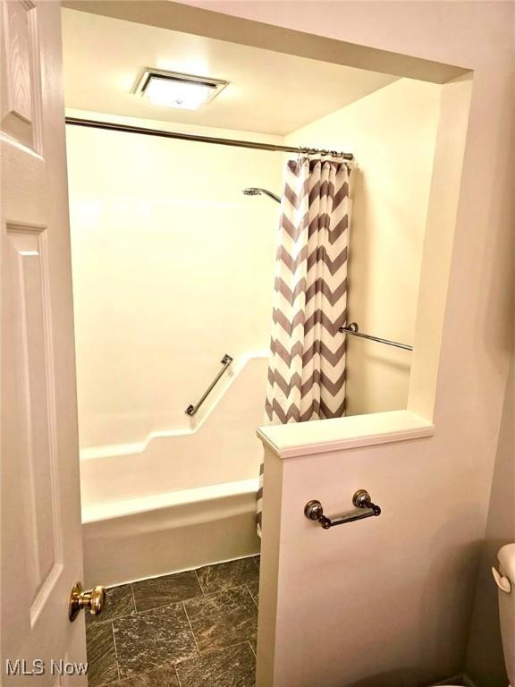 full bathroom featuring visible vents, toilet, stone finish floor, and shower / bath combination with curtain