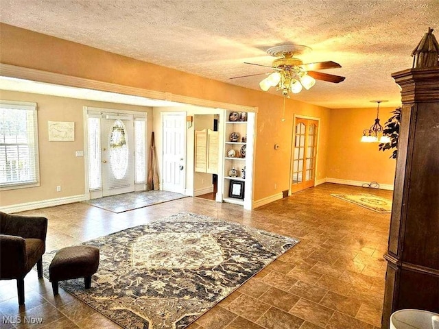 entrance foyer featuring stone finish floor, a ceiling fan, baseboards, and a textured ceiling