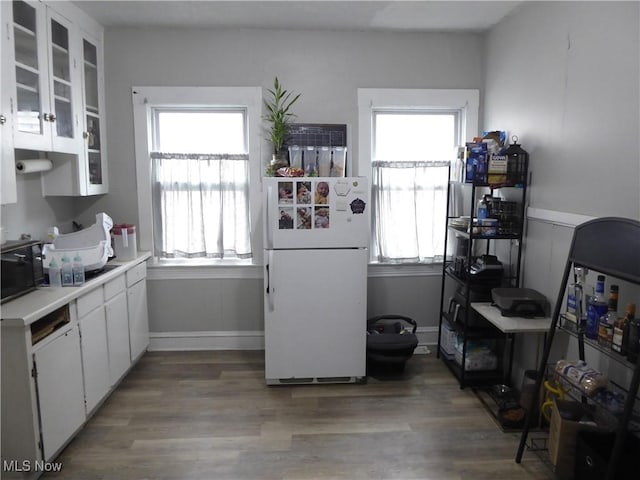 kitchen with white cabinets, wood finished floors, freestanding refrigerator, and black microwave