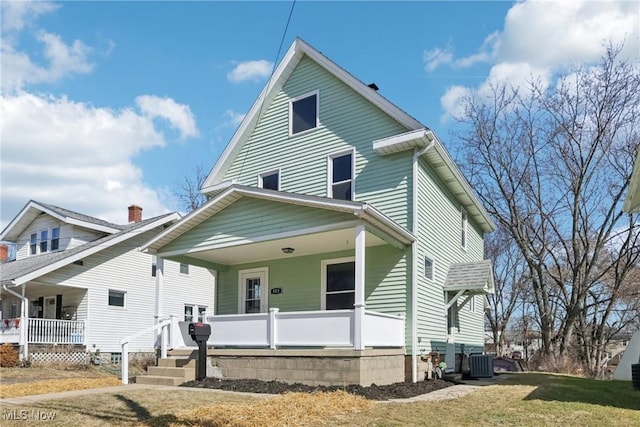 view of front of house with a front yard, covered porch, and central AC