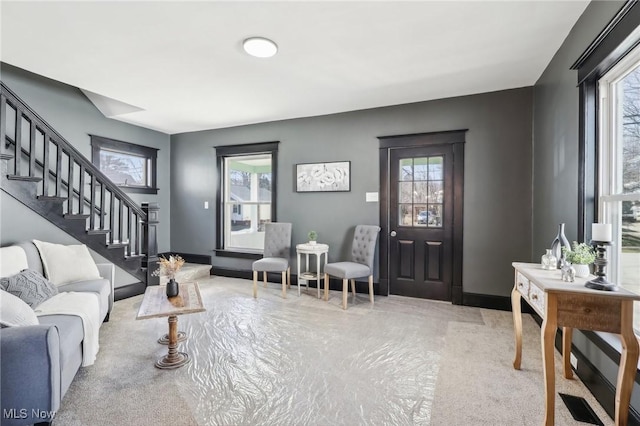 living area with a wealth of natural light, stairway, and baseboards