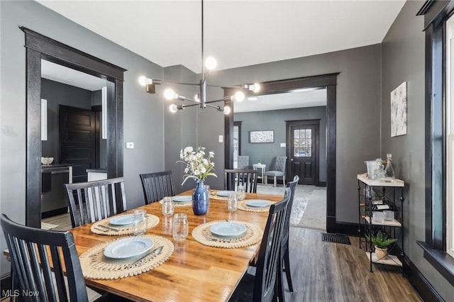 dining area with baseboards, an inviting chandelier, and wood finished floors