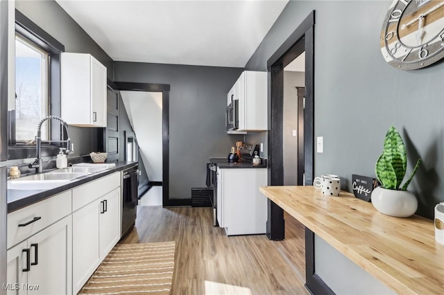 kitchen featuring light wood-type flooring, a sink, stainless steel microwave, white cabinetry, and dishwasher