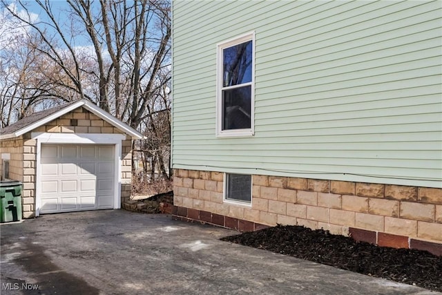 view of side of home featuring driveway, a detached garage, and an outdoor structure