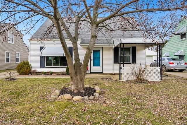 view of front of home with a front lawn, driveway, a garage, and roof with shingles