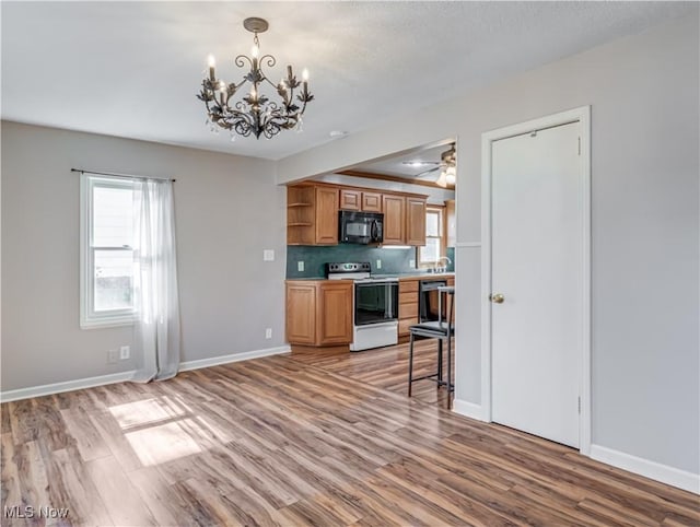 kitchen featuring open shelves, decorative backsplash, light wood-style floors, and black appliances