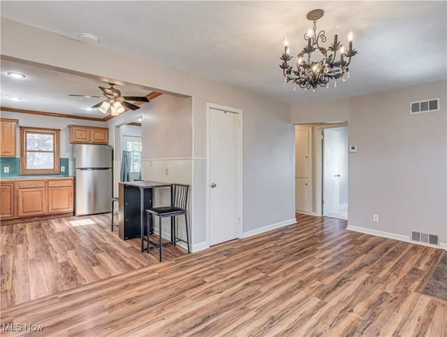 unfurnished living room with light wood-type flooring, visible vents, baseboards, and ceiling fan with notable chandelier