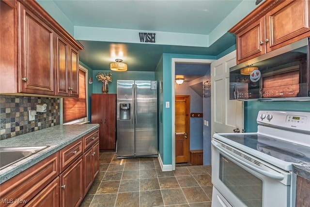 kitchen featuring brown cabinetry, baseboards, a sink, stainless steel appliances, and tasteful backsplash