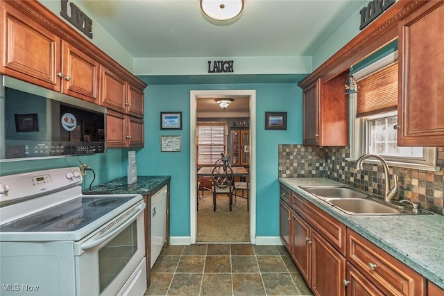 kitchen featuring electric range, a sink, stainless steel microwave, tasteful backsplash, and baseboards