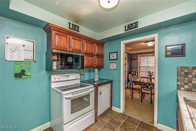 kitchen featuring baseboards, white appliances, brown cabinets, and dark carpet