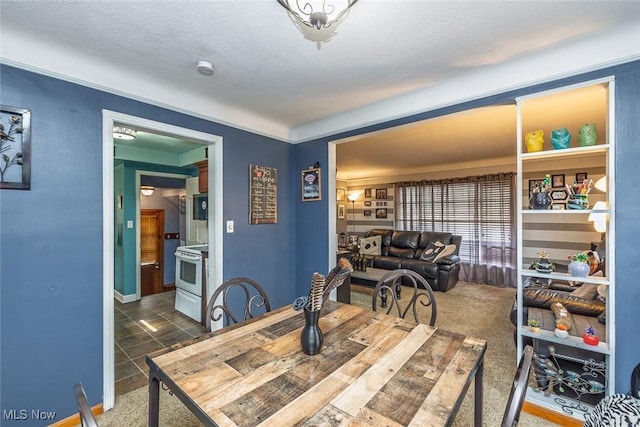 dining area featuring baseboards, dark colored carpet, and a textured ceiling