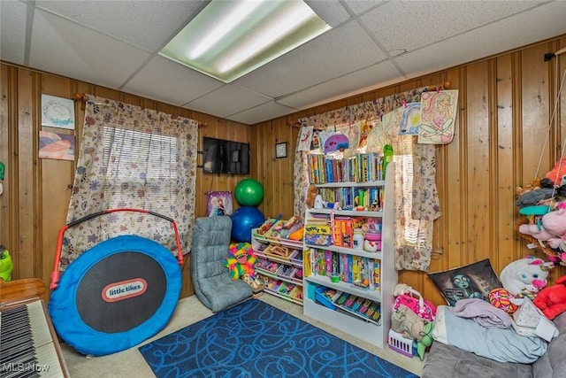 game room with a paneled ceiling and wooden walls