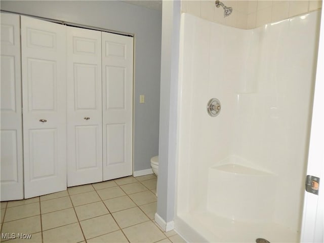 bathroom featuring a shower, tile patterned flooring, toilet, and a closet