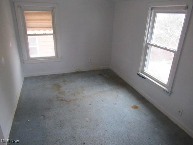 carpeted spare room with a healthy amount of sunlight and baseboards