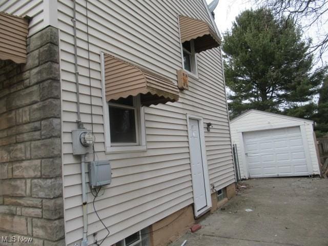 view of home's exterior with a detached garage, an outdoor structure, and concrete driveway