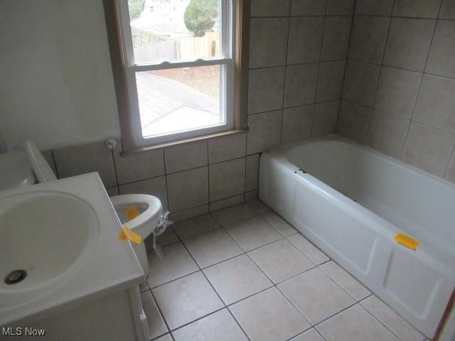 full bath with vanity, a tub, tile patterned flooring, tile walls, and toilet