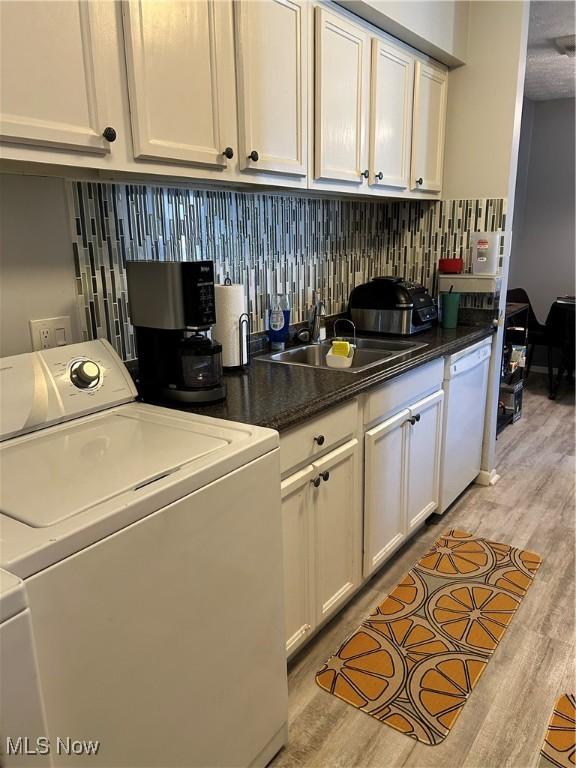 clothes washing area featuring light wood finished floors, laundry area, independent washer and dryer, and a sink