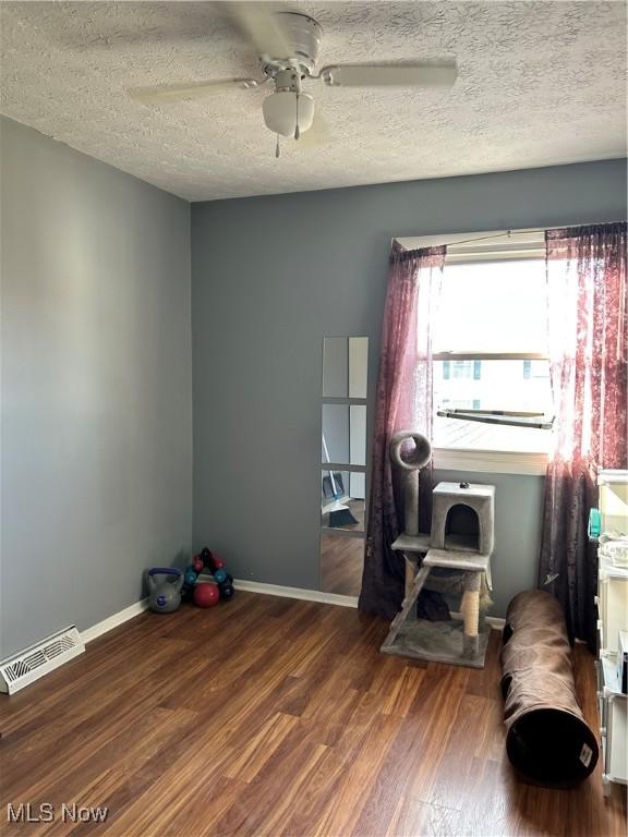 office area with visible vents, baseboards, ceiling fan, wood finished floors, and a textured ceiling