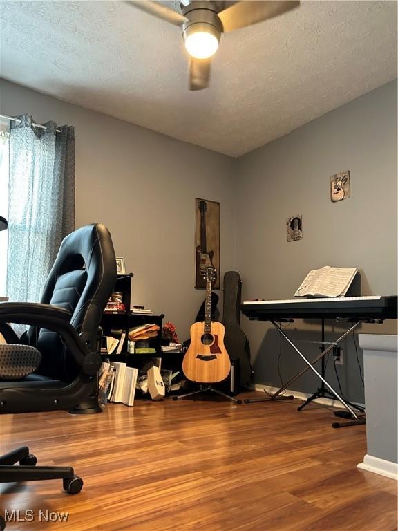 home office featuring a textured ceiling, wood finished floors, and a ceiling fan