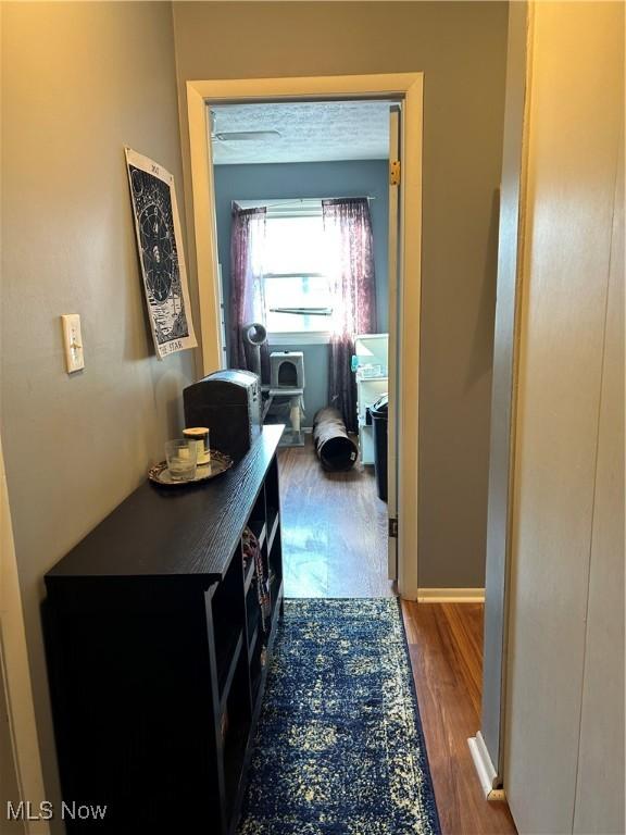 hallway featuring dark wood finished floors and baseboards