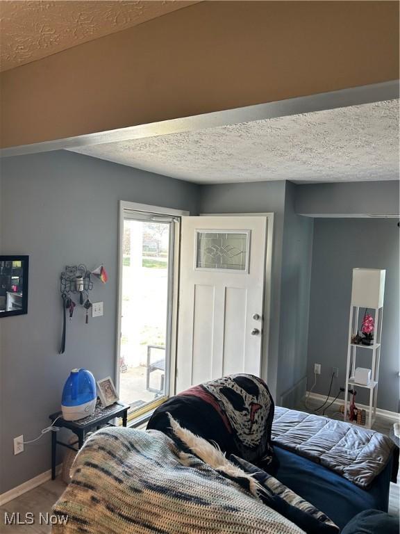 bedroom with wood finished floors, baseboards, and a textured ceiling