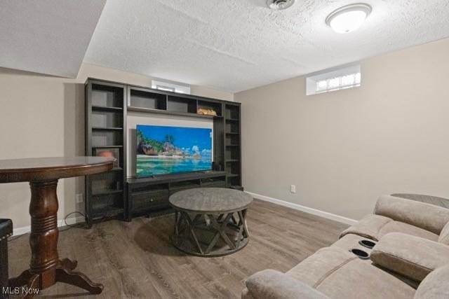 living area featuring a textured ceiling, baseboards, and wood finished floors