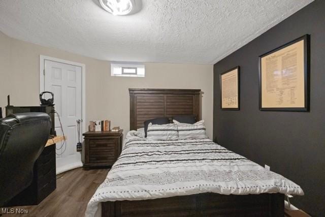 bedroom with a textured ceiling and dark wood-style flooring