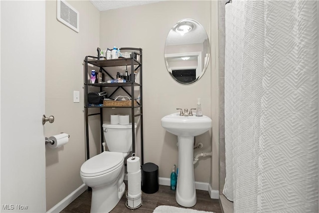 full bathroom featuring a shower with shower curtain, wood finished floors, visible vents, baseboards, and toilet