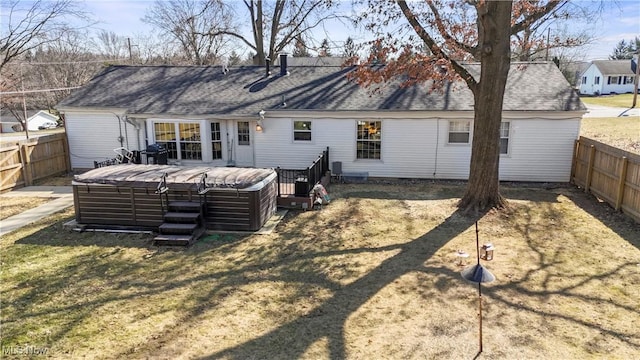 back of house with a shingled roof, a deck, and fence