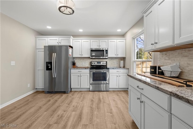 kitchen featuring white cabinets, light wood-type flooring, backsplash, and stainless steel appliances