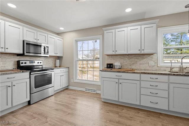 kitchen featuring visible vents, light wood-style flooring, a sink, white cabinetry, and stainless steel appliances